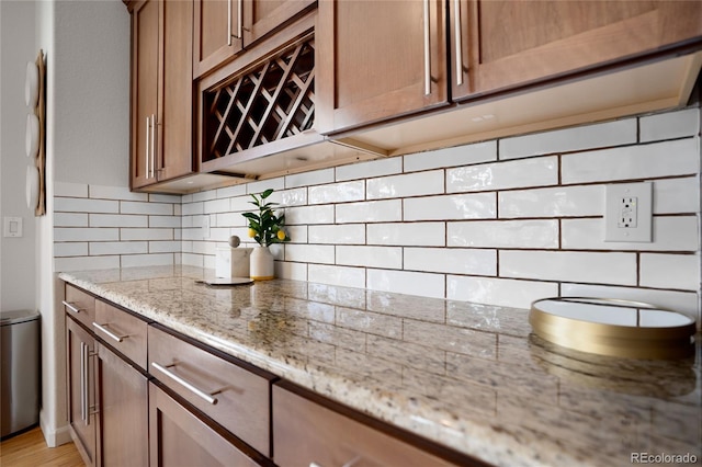 15502 E Flower Mound Pl, Parker, CO 80134 - kitchen with backsplash, light stone counters, and brown cabinetry