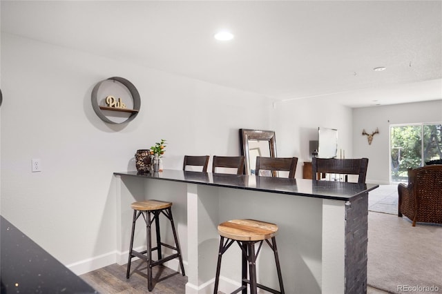 15502 E Flower Mound Pl, Parker, CO 80134 - kitchen featuring a kitchen bar, recessed lighting, dark countertops, and a peninsula
