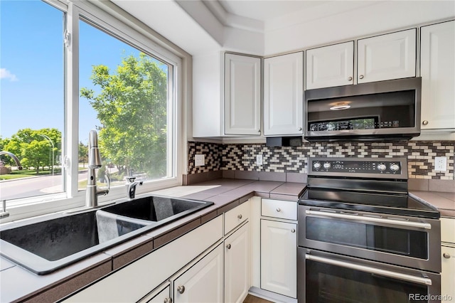1526 Braewood Ave, Littleton, CO 80129 - kitchen with appliances with stainless steel finishes, a sink, white cabinets, backsplash, and tile counters