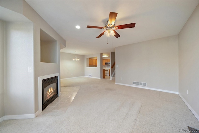 unfurnished living room with light colored carpet and ceiling fan with notable chandelier