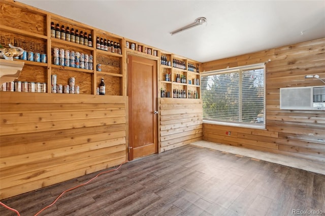 spare room featuring an AC wall unit, wood walls, and dark wood-type flooring