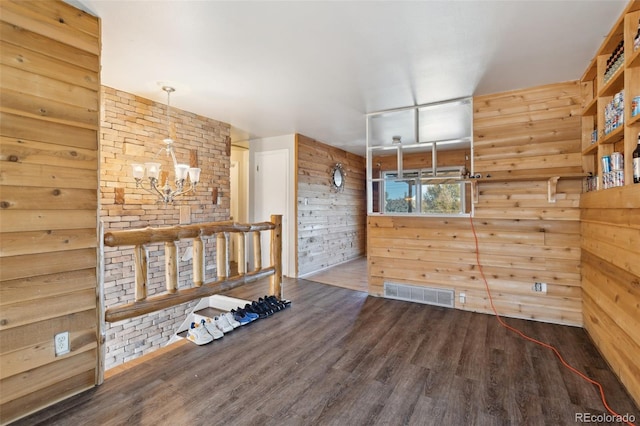 interior space with wooden walls, dark wood-type flooring, and a notable chandelier