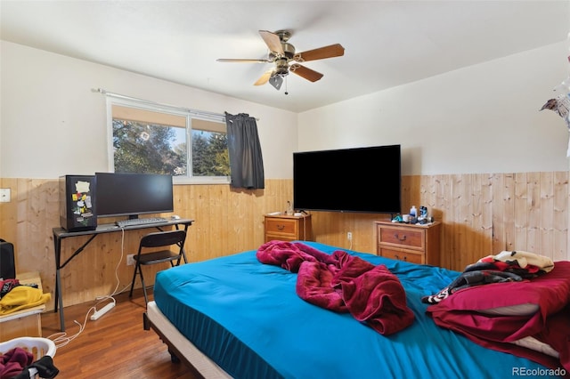 bedroom featuring ceiling fan, wood walls, and dark wood-type flooring