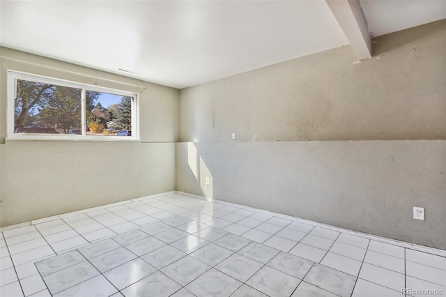 tiled empty room featuring vaulted ceiling with beams