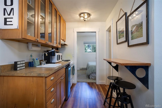 3295 Apres Ski Way Unit B9, Steamboat Springs, CO 80487 - kitchen with brown cabinets, dark wood-type flooring, glass insert cabinets, and dark countertops