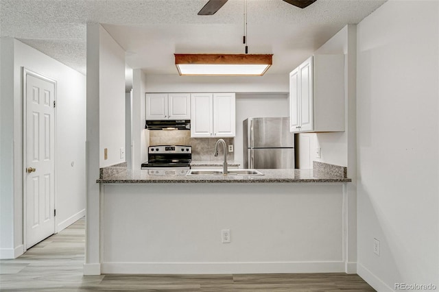 kitchen featuring sink, stainless steel appliances, dark stone counters, a textured ceiling, and white cabinets