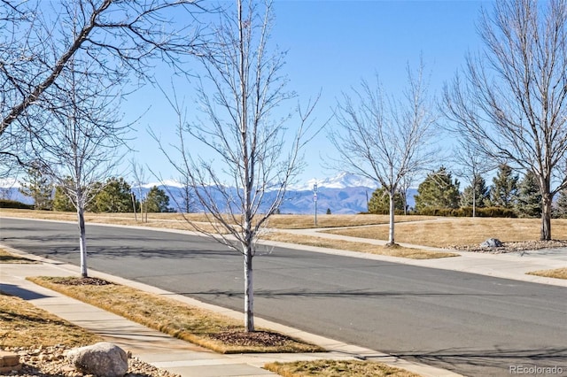 view of road with curbs, a mountain view, and sidewalks