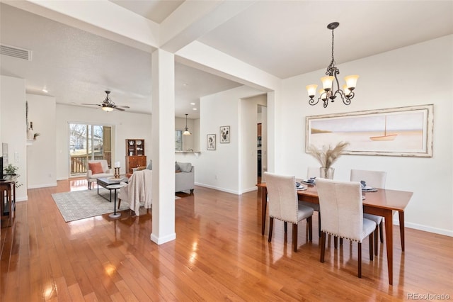 dining area featuring ceiling fan with notable chandelier, hardwood / wood-style flooring, visible vents, and baseboards