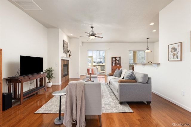 living area with recessed lighting, a fireplace, wood finished floors, visible vents, and baseboards