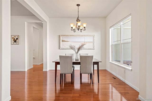 dining room with a chandelier, visible vents, baseboards, and wood finished floors