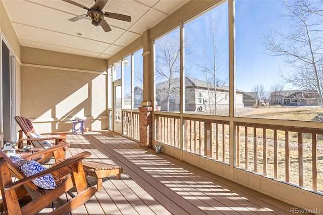 sunroom featuring a healthy amount of sunlight, a residential view, and a ceiling fan