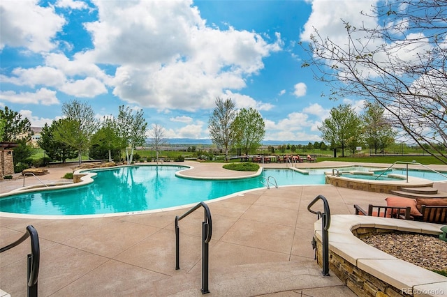 community pool with a patio area and a hot tub