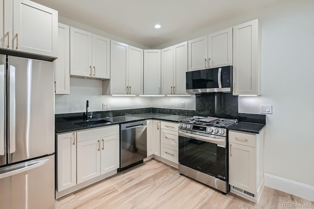 715 W 7th Ave, Denver, CO 80204 - kitchen with stainless steel appliances, light wood-type flooring, dark stone counters, white cabinetry, and backsplash