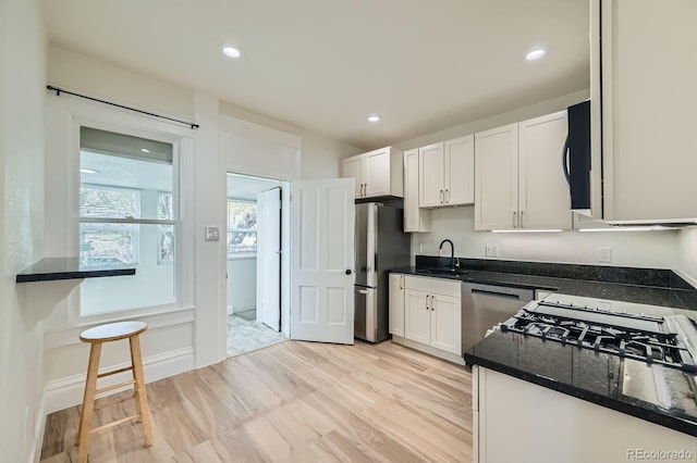 715 W 7th Ave, Denver, CO 80204 - kitchen with freestanding refrigerator, dishwasher, white cabinets, black microwave, and light wood-type flooring