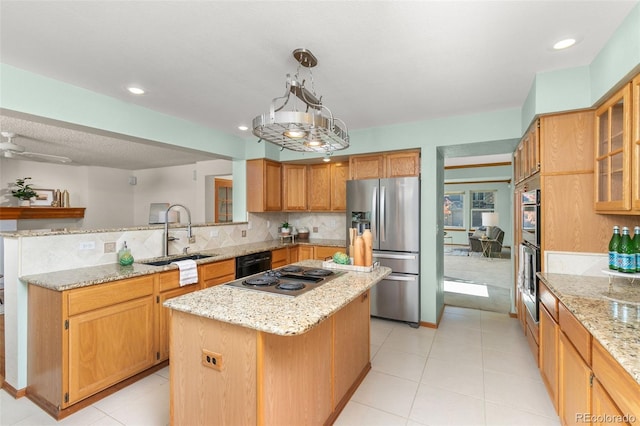 kitchen featuring decorative light fixtures, sink, decorative backsplash, a center island, and black appliances