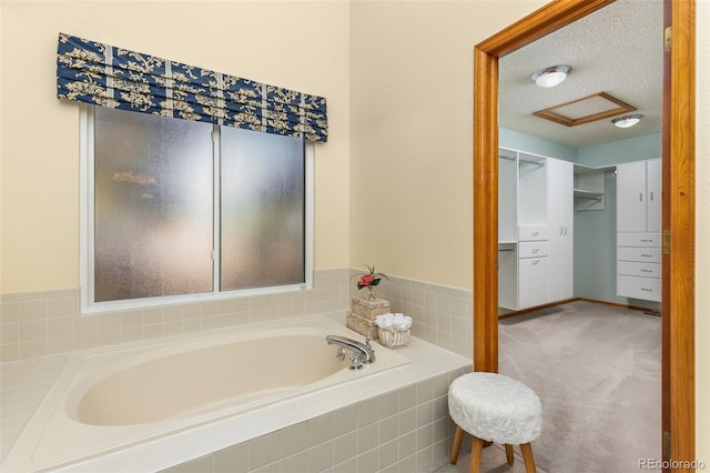 bathroom with a relaxing tiled tub and a textured ceiling