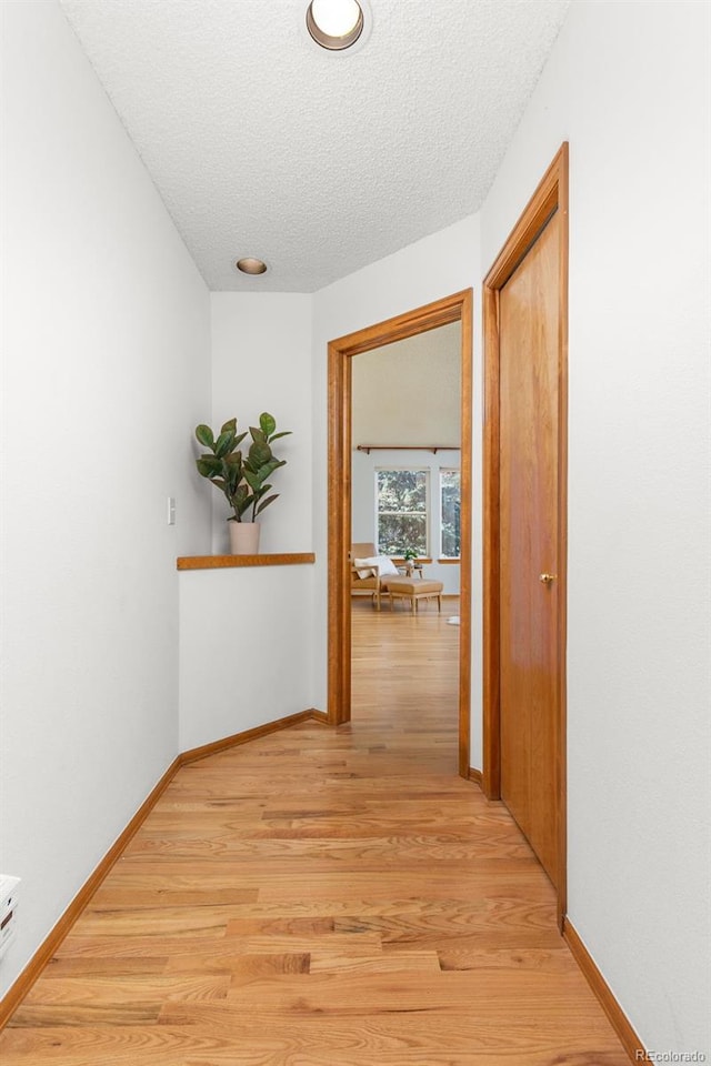 corridor featuring a textured ceiling and light wood-type flooring