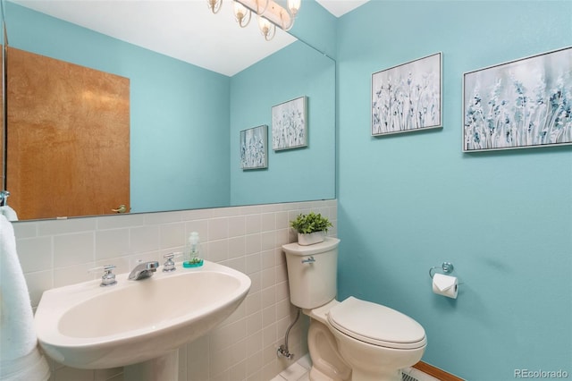 bathroom featuring sink, tile walls, and toilet