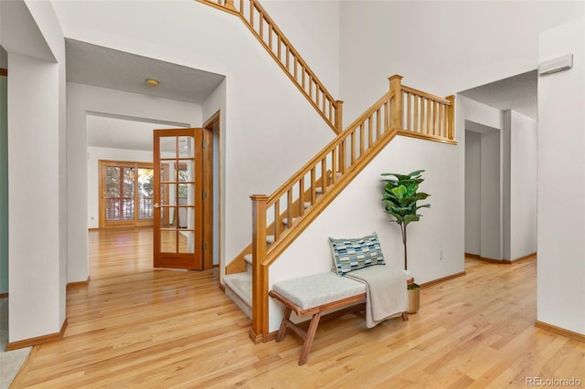 stairway with french doors, a towering ceiling, and hardwood / wood-style floors