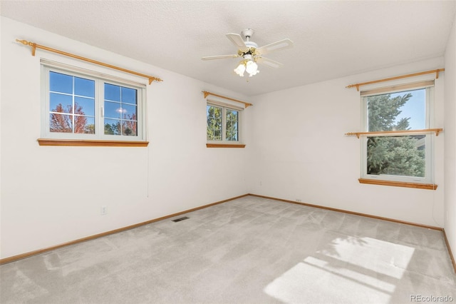 unfurnished room with light carpet, ceiling fan, and a textured ceiling