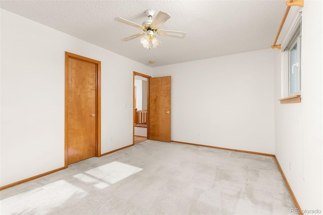 spare room featuring ceiling fan, light colored carpet, and a textured ceiling