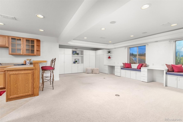 carpeted living room featuring built in desk and a tray ceiling