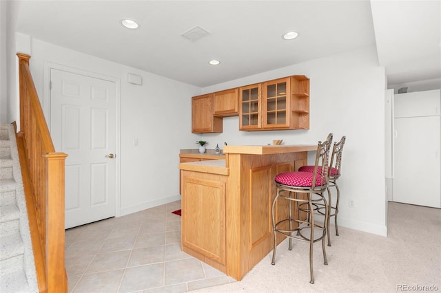 kitchen featuring a breakfast bar, kitchen peninsula, and light tile patterned floors