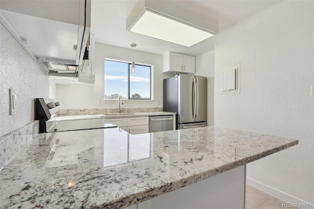 kitchen featuring appliances with stainless steel finishes, white cabinetry, sink, kitchen peninsula, and light stone counters