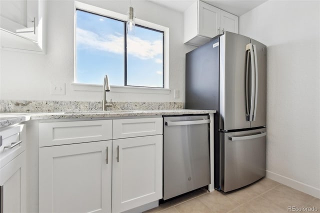 kitchen with sink, light tile patterned floors, stainless steel appliances, white cabinets, and light stone counters