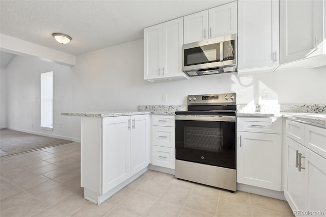 kitchen with kitchen peninsula, light tile patterned floors, appliances with stainless steel finishes, a textured ceiling, and white cabinets