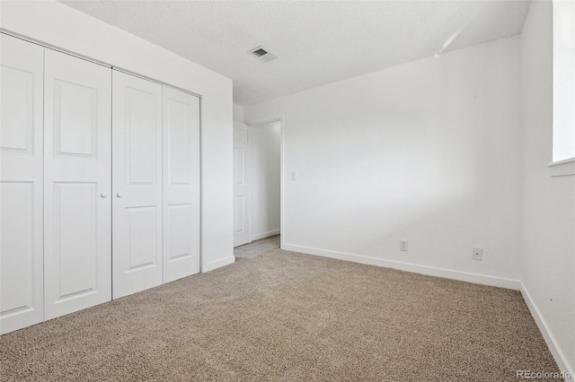 unfurnished bedroom featuring a textured ceiling, a closet, and carpet