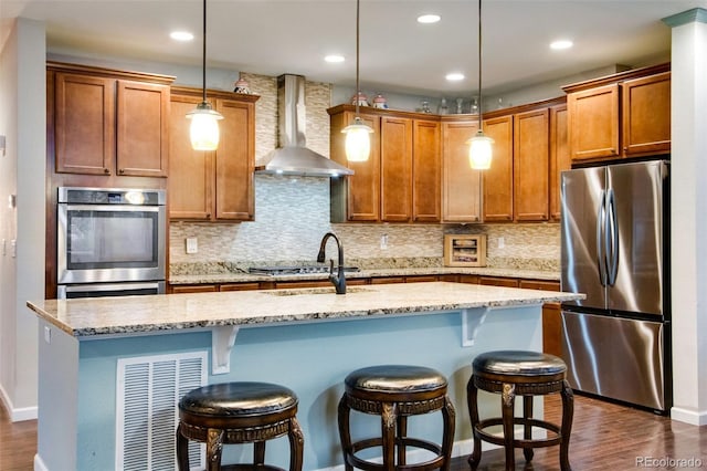2415 Bluestem Willow Dr, Loveland, CO 80538 - kitchen featuring stainless steel appliances, wall chimney exhaust hood, a kitchen island with sink, a sink, and tasteful backsplash