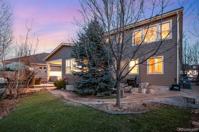 2415 Bluestem Willow Dr, Loveland, CO 80538 - back of house at dusk featuring a lawn and central AC