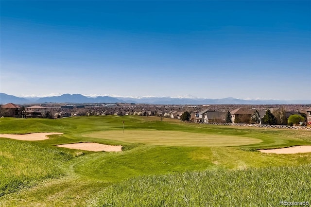 view of property's community with a yard, view of golf course, and a mountain view