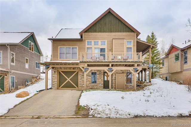 view of front of house with an attached garage, stone siding, and driveway