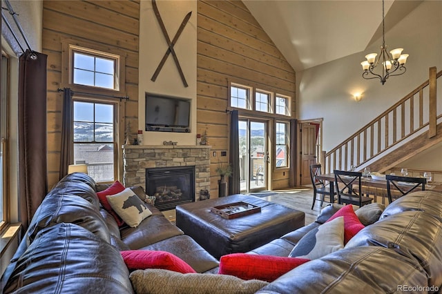 living area featuring wood finished floors, a stone fireplace, wood walls, a chandelier, and stairs