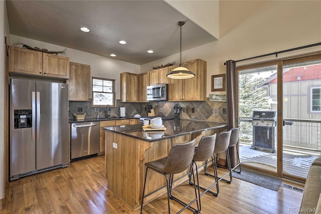 kitchen with light wood-type flooring, stainless steel appliances, tasteful backsplash, and a sink