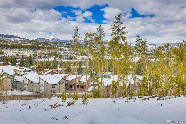 snowy aerial view featuring a mountain view and a residential view