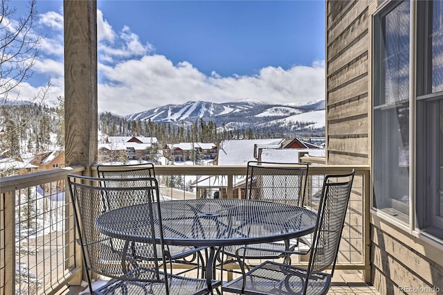 snow covered back of property with a mountain view and outdoor dining space