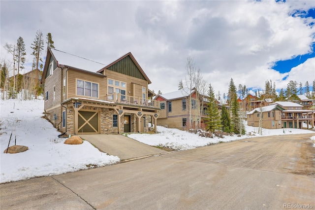 view of front of home with stone siding, an attached garage, board and batten siding, and driveway