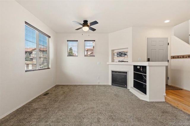 7046 Sand Crest Vw, Colorado Springs, CO 80923 - unfurnished living room featuring a ceiling fan, carpet, a glass covered fireplace, and baseboards