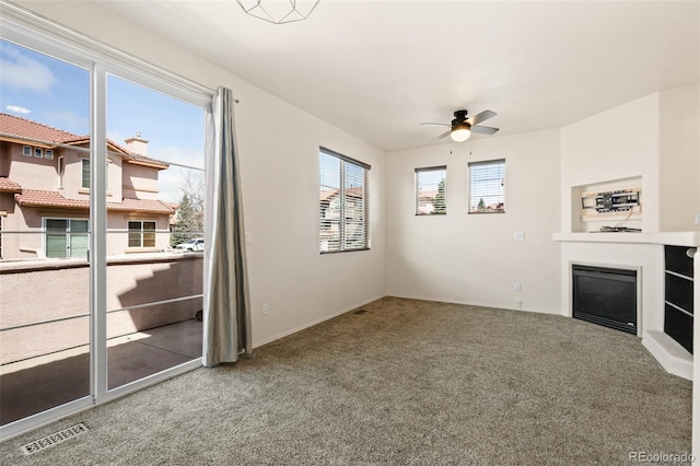 7046 Sand Crest Vw, Colorado Springs, CO 80923 - unfurnished living room with carpet flooring, ceiling fan, a glass covered fireplace, and baseboards