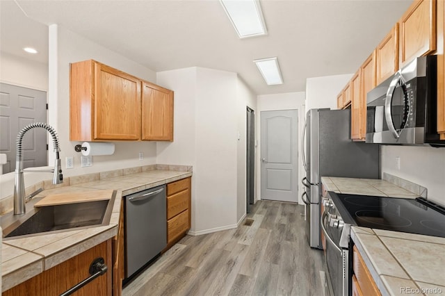 7046 Sand Crest Vw, Colorado Springs, CO 80923 - kitchen with stainless steel appliances, a sink, light wood-style flooring, tile counters, and recessed lighting