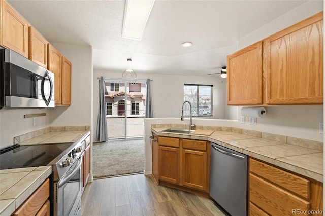 7046 Sand Crest Vw, Colorado Springs, CO 80923 - kitchen with stainless steel appliances, a sink, light wood-type flooring, a peninsula, and a ceiling fan