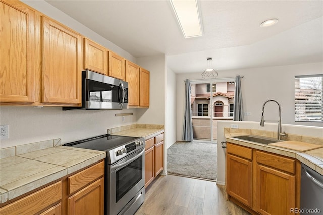7046 Sand Crest Vw, Colorado Springs, CO 80923 - kitchen with stainless steel appliances, a sink, light wood-type flooring, and hanging light fixtures