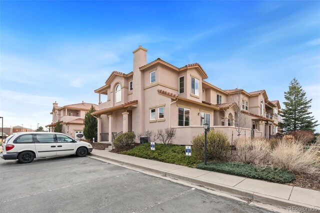 7046 Sand Crest Vw, Colorado Springs, CO 80923 - view of front of house featuring a chimney, uncovered parking, stucco siding, and a tiled roof
