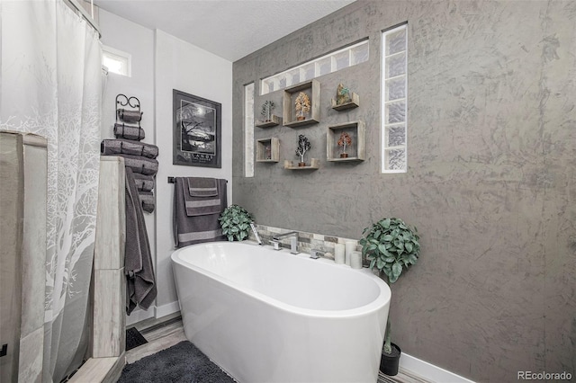 bathroom with a textured ceiling and a tub to relax in