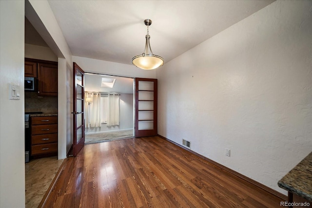 unfurnished dining area with dark hardwood / wood-style floors and french doors