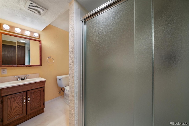 bathroom featuring vanity, toilet, a shower with door, and a textured ceiling