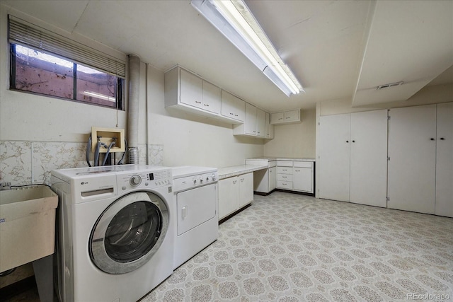 washroom featuring sink, cabinets, and independent washer and dryer